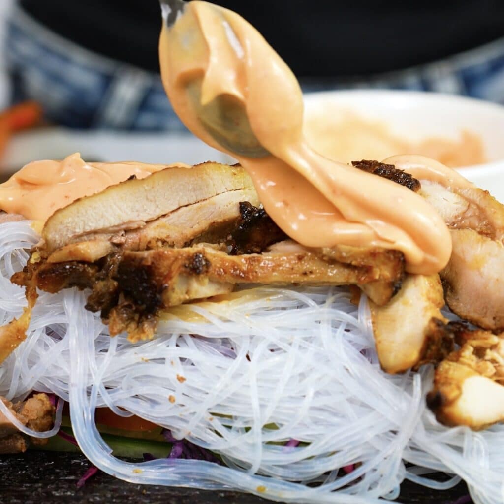 Drizzling sriracha mayo over the filling on rice paper