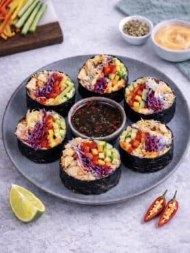 Sliced rice paper chicken nori rolls served on a plate with dipping sauce