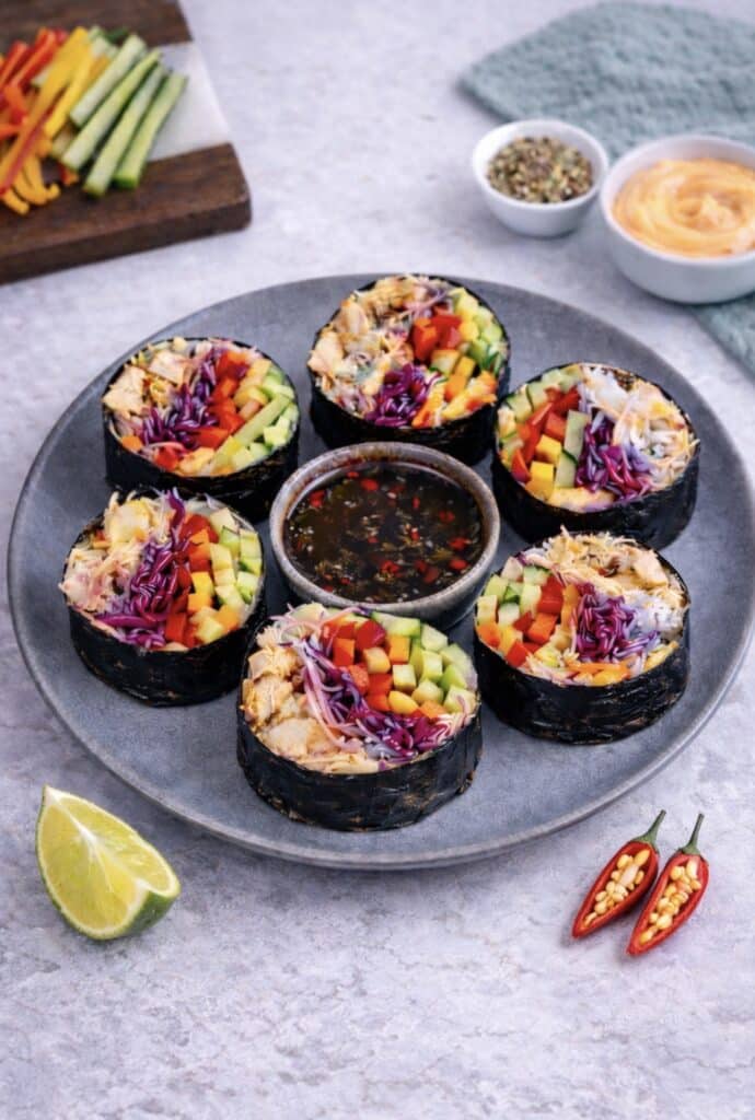 Sliced rice paper chicken nori rolls served on a plate with dipping sauce