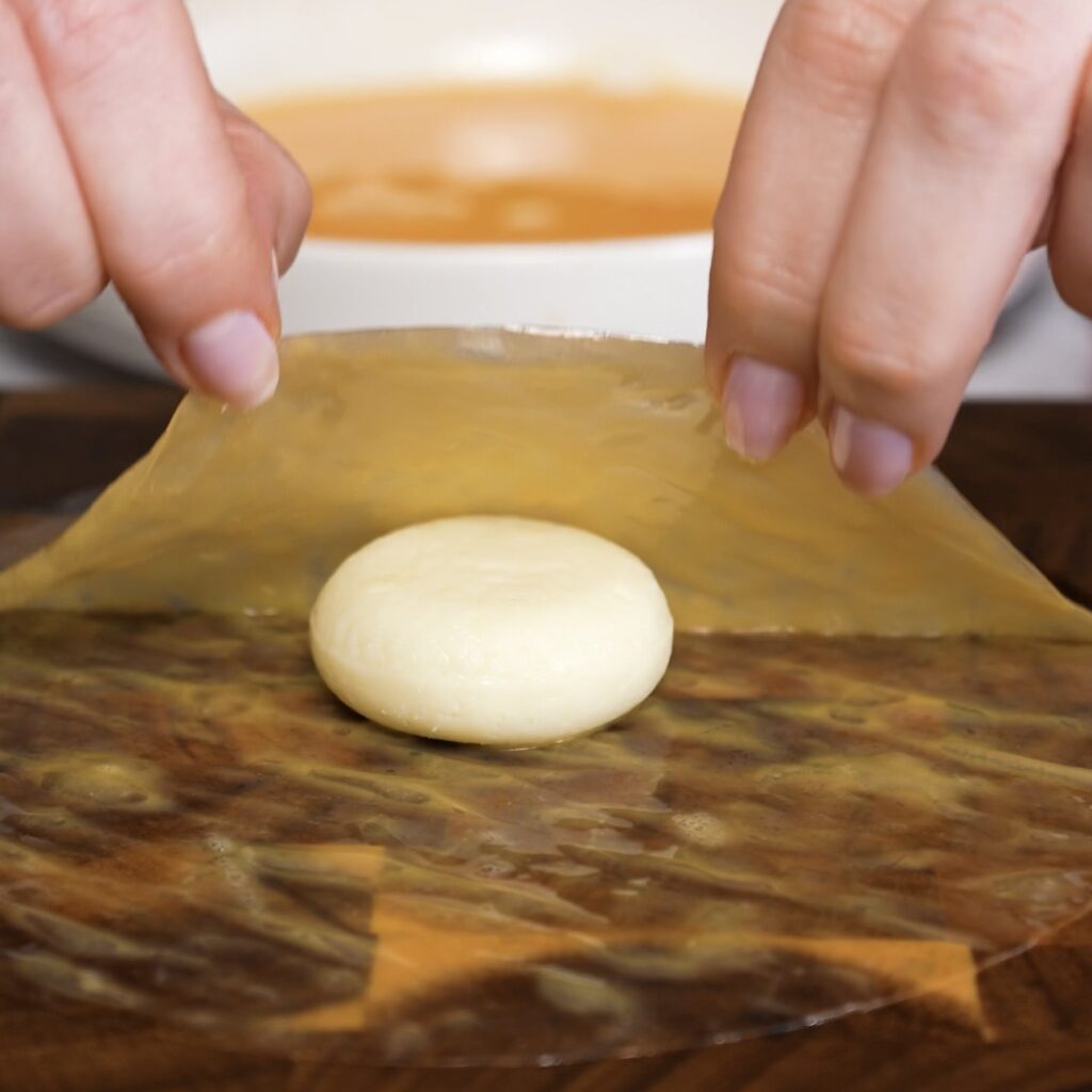 Babybel cheese placed on egg-coated rice paper ready for wrapping