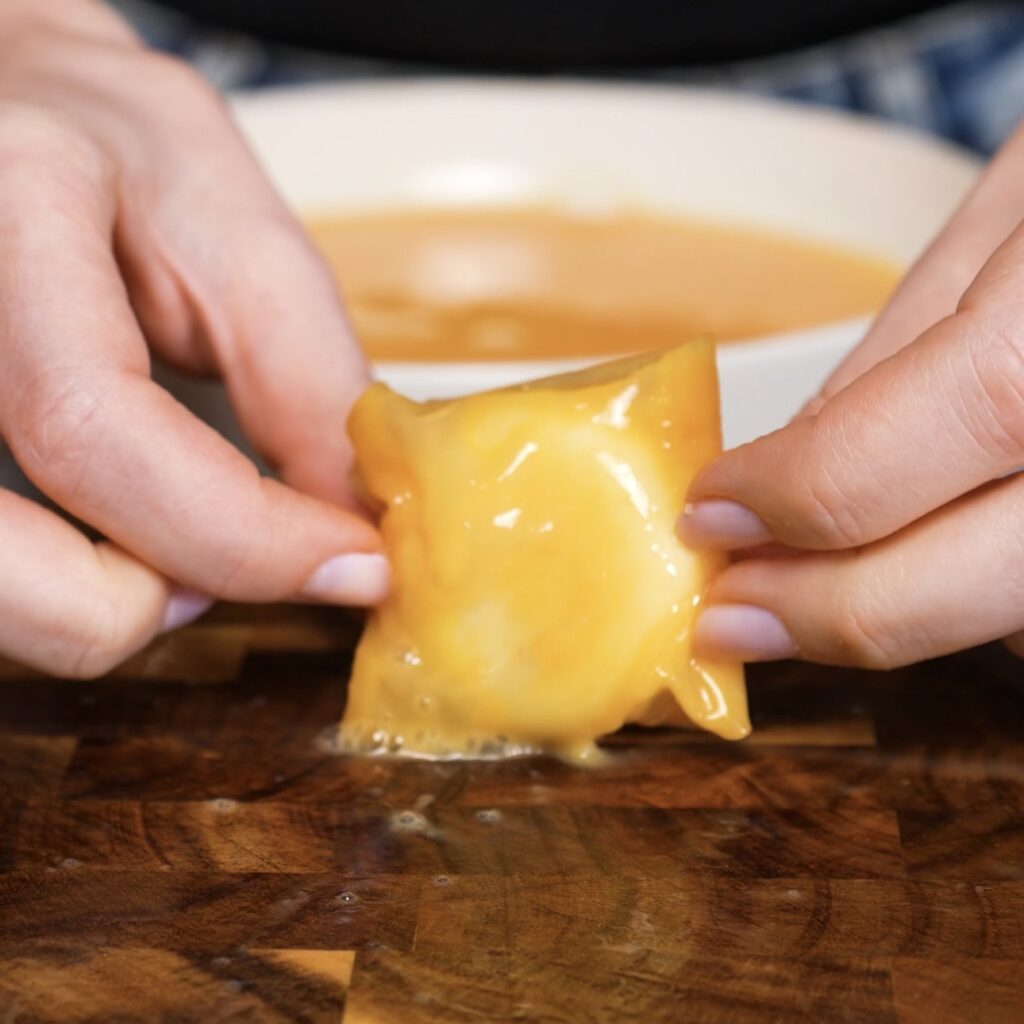 Babybel cheese fully wrapped in first layer of egg-dipped rice paper