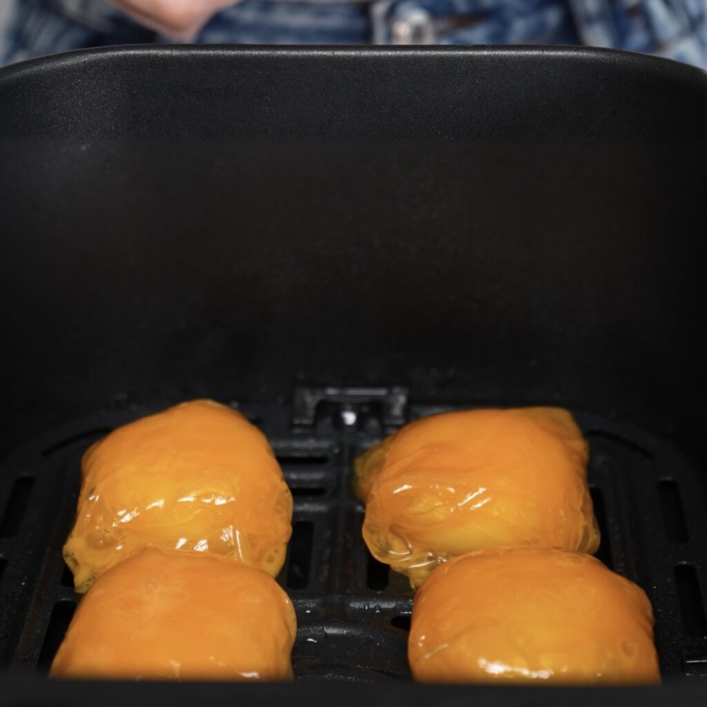 Rice paper wrapped Babybel cheese balls in air fryer basket before cooking