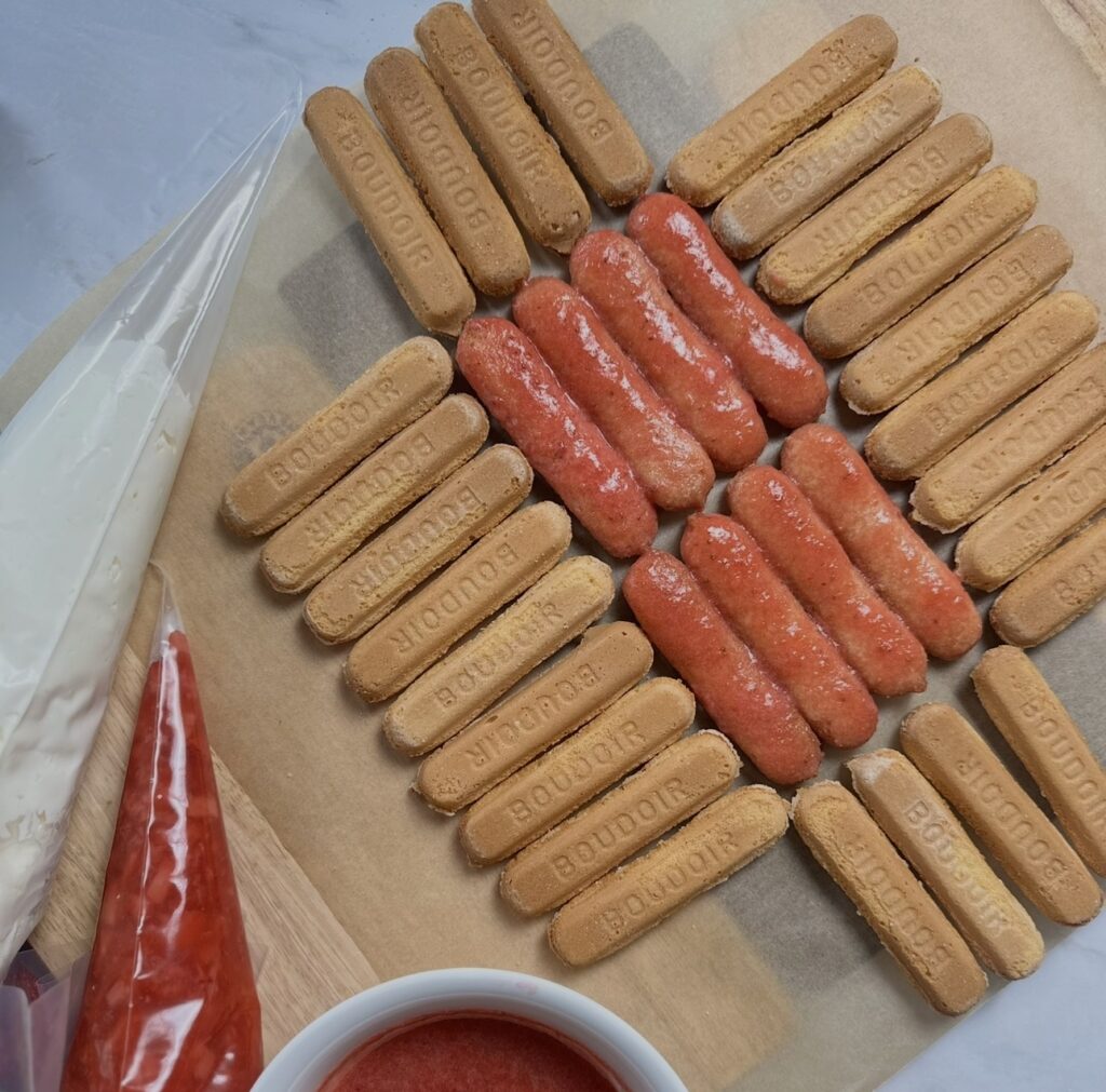 Arranging dipped sponge fingers in two rows with undipped sponge fingers around the edges