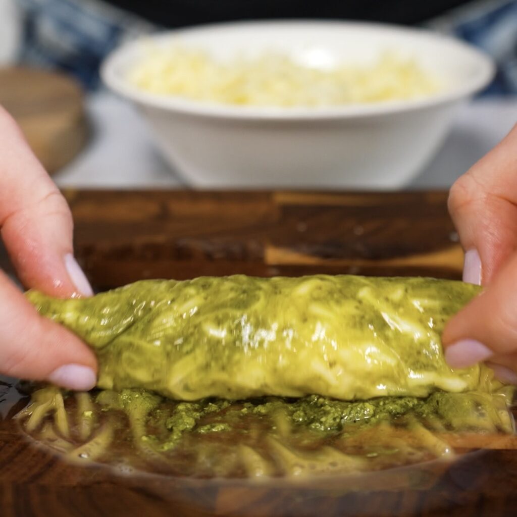 Rolling rice paper around pesto and mozzarella filling into a tight stick