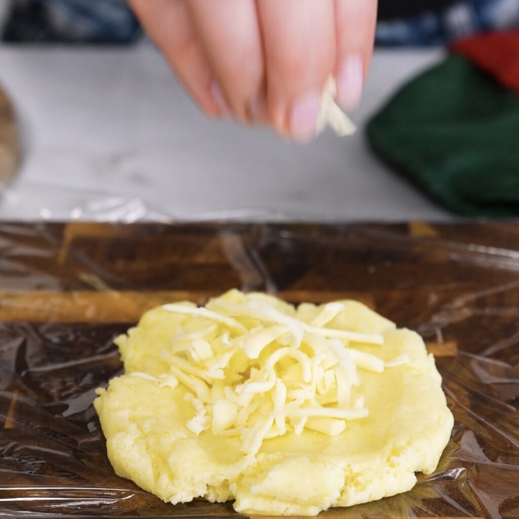 Adding mozzarella to flattened potato dough before shaping