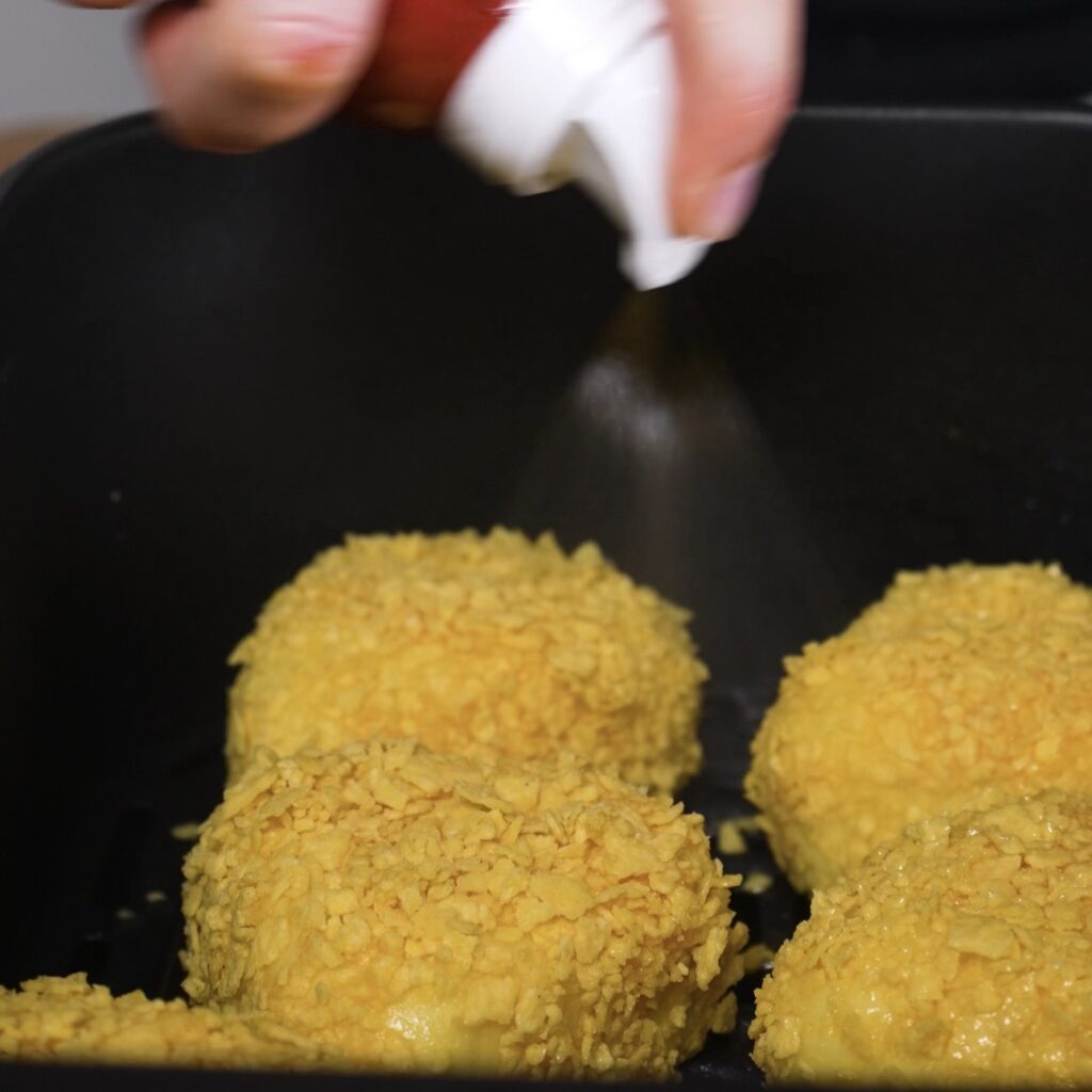 Spraying potato triangles with olive oil before air frying
