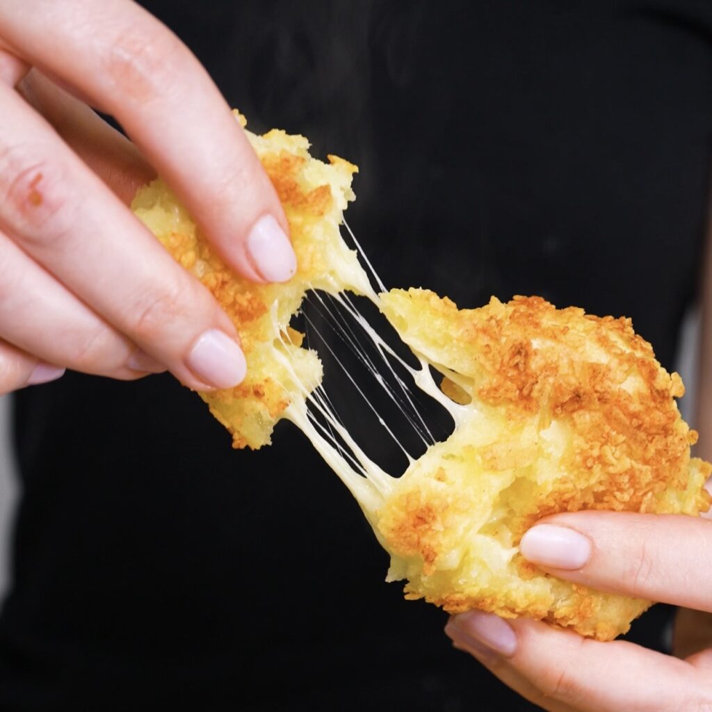 Cheese pull from crispy potato triangle showing melted mozzarella