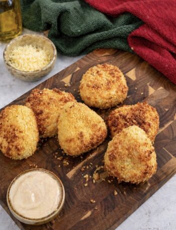 Air fryer cheesy potato triangles served on a wooden board with dipping sauce