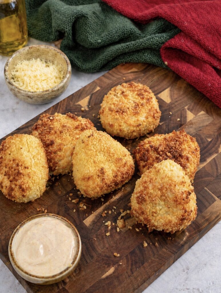 Air fryer cheesy potato triangles served on a wooden board with dipping sauce