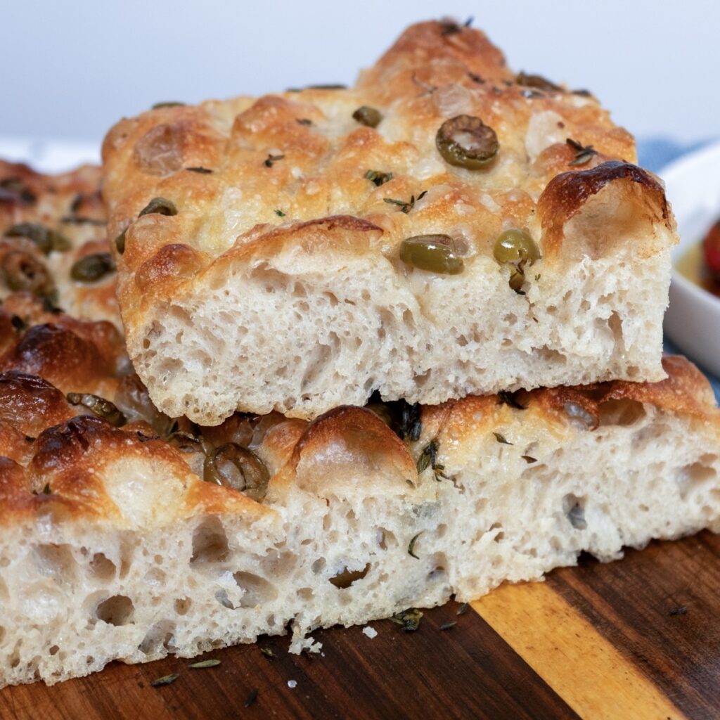 Sliced focaccia showing soft airy crumb with open holes and golden crust