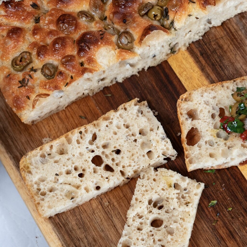 Sliced focaccia showing soft airy crumb with open holes and golden crust