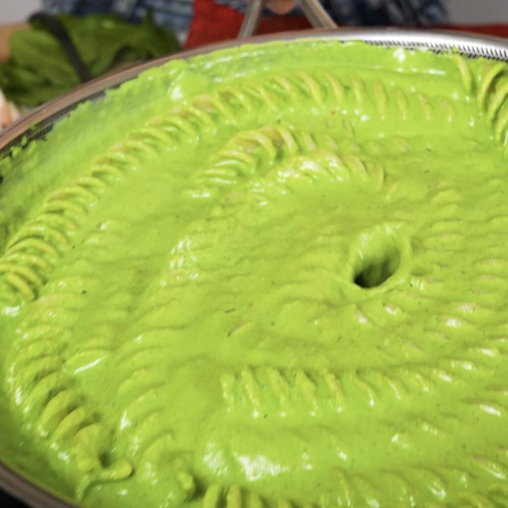 Pasta cooking in creamy spinach ricotta sauce in a pan