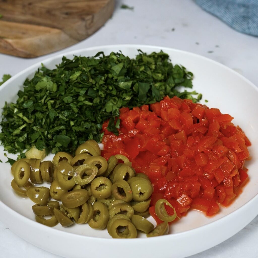 Chopped roasted red peppers, olives, garlic, and fresh coriander prepared for roasted red pepper olive dip
