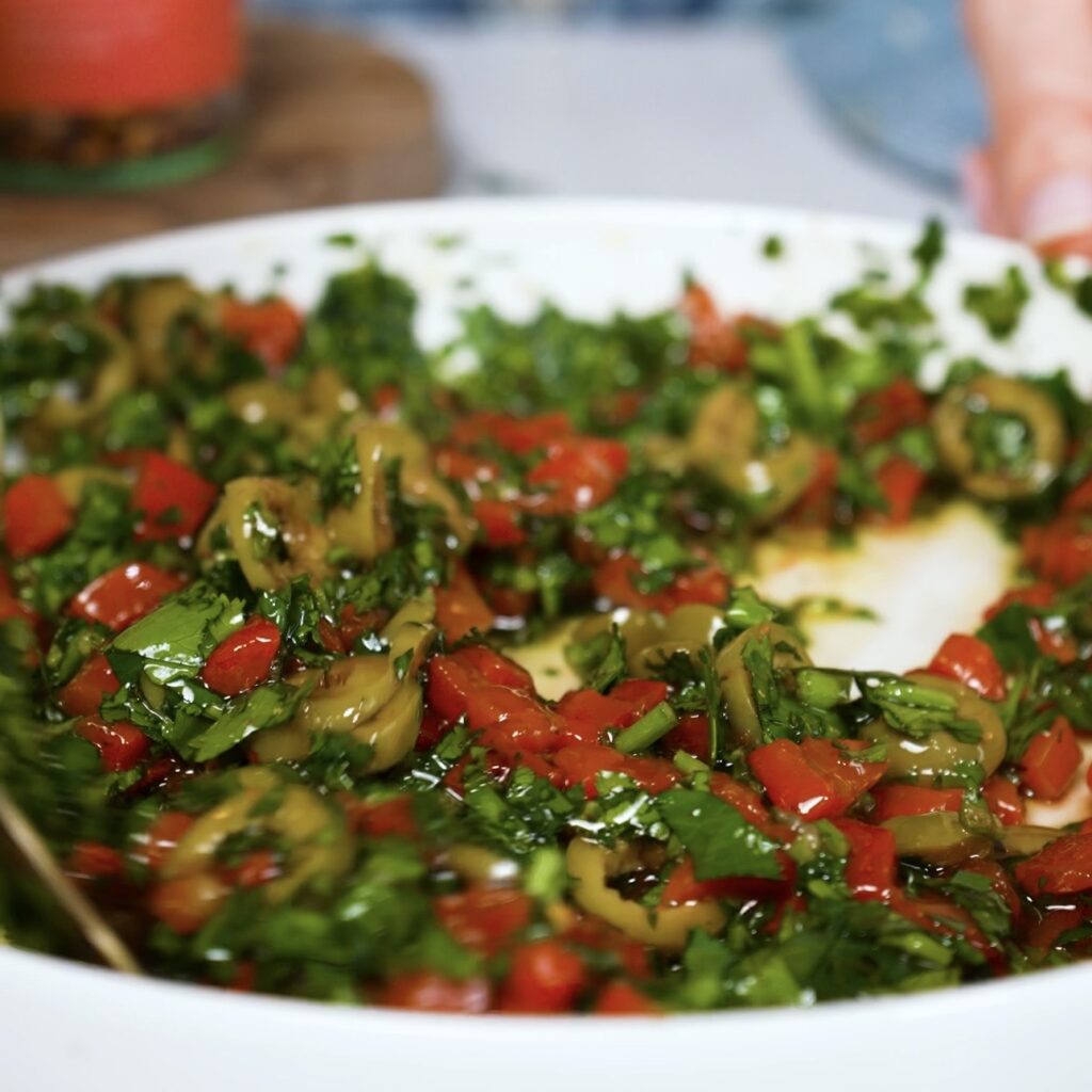 Mixed roasted red pepper olive dip with chopped olives, coriander, and garlic in a bowl