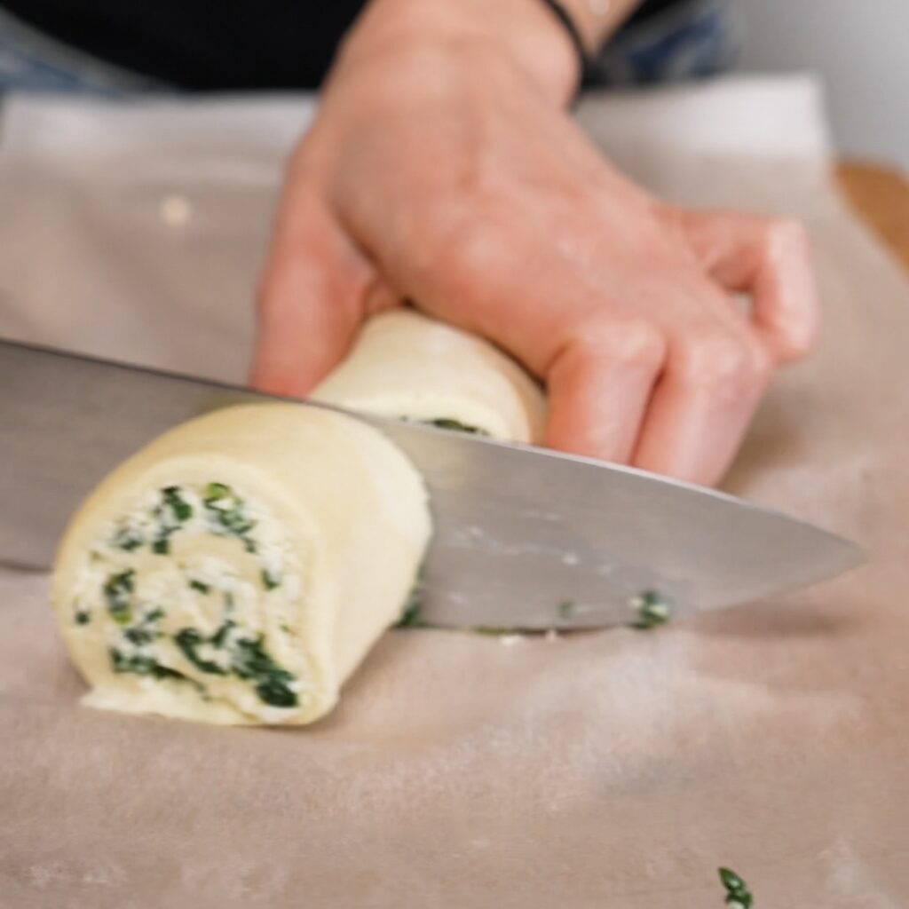 Cutting spinach and feta puff pastry log into rolls