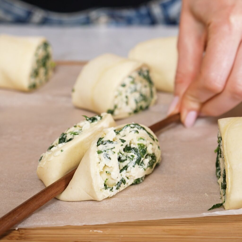 Pressing a chopstick into spinach and feta puff pastry rolls