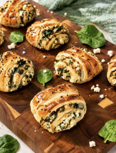 Spinach and feta puff pastry rolls served on a wooden board