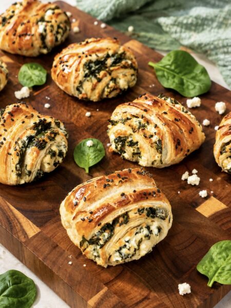 Spinach and feta puff pastry rolls served on a wooden board
