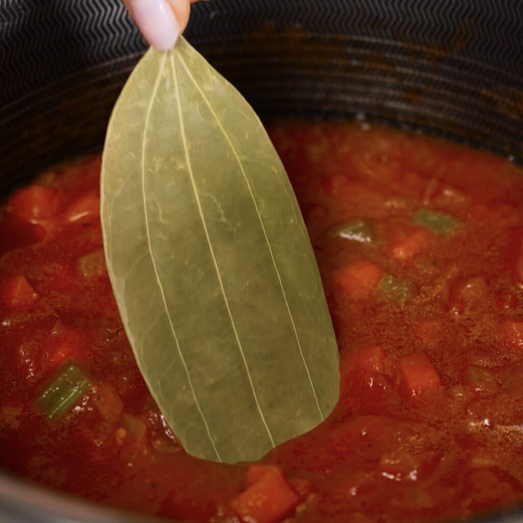Adding a bay leaf to homemade tomato sauce for stuffed Caccavelle pasta bake