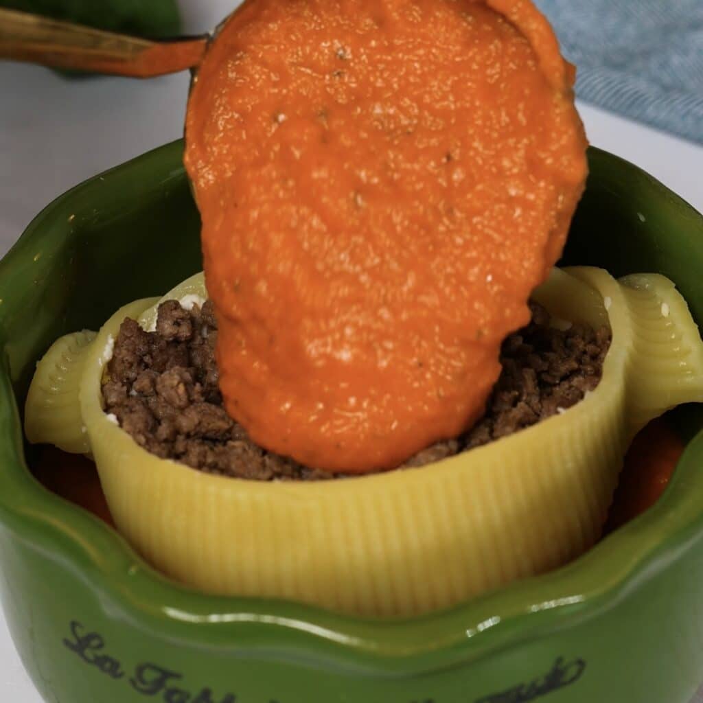 Adding the final layer of tomato sauce inside stuffed Caccavelle pasta
