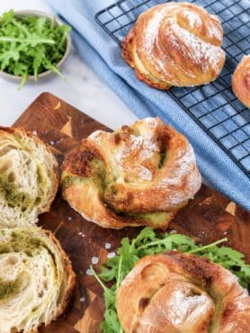 Freshly baked No-Knead Pesto Mozzarella Bread Twists served on a wooden board.