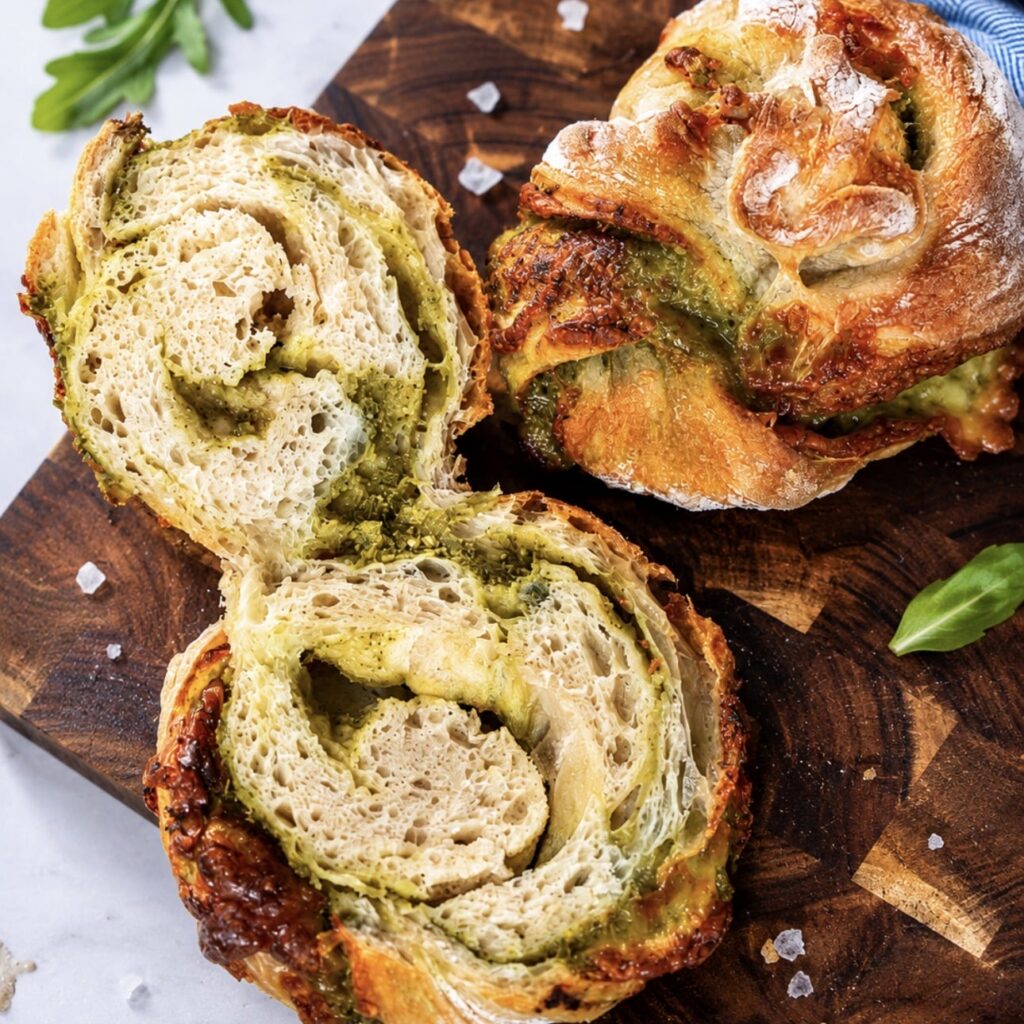 Sliced No-Knead Pesto Mozzarella Bread Twist on a wooden board showing the soft, airy interior.