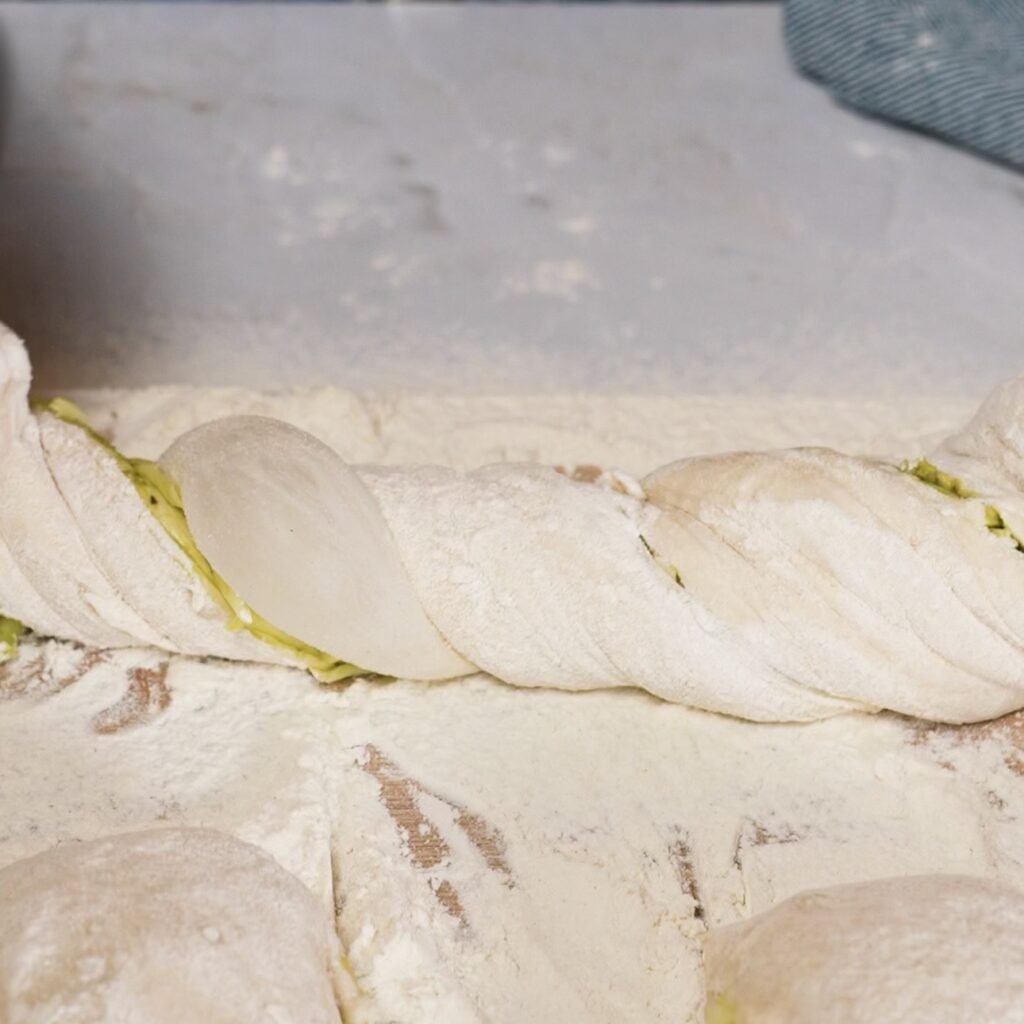 Pesto mozzarella dough strip stretched and twisted a few times on a floured work surface.