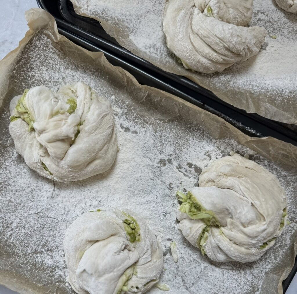 Pesto mozzarella bread twists on a baking tray before the final proof.