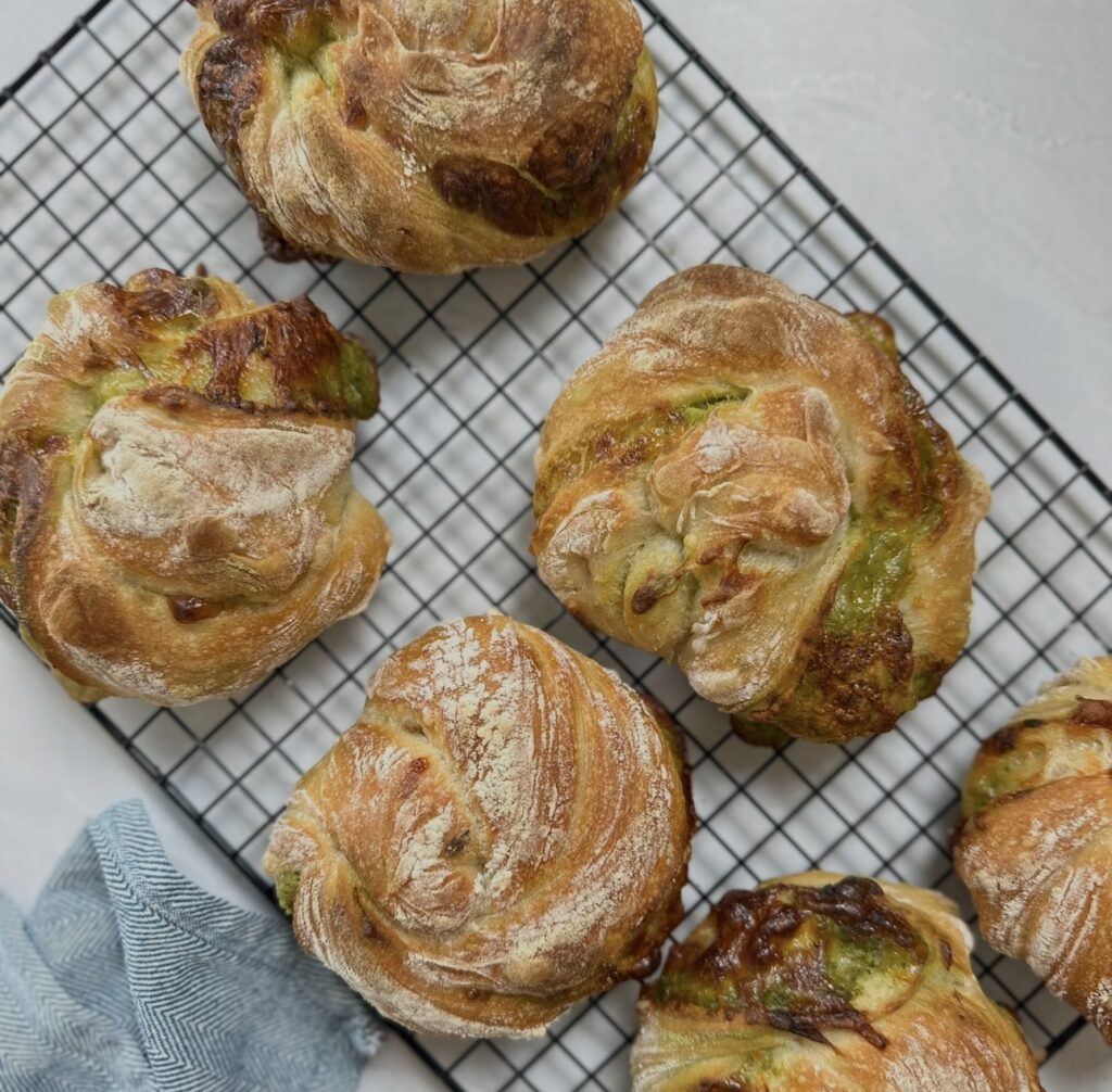 Freshly baked pesto mozzarella bread twists cooling on a wire rack after baking.