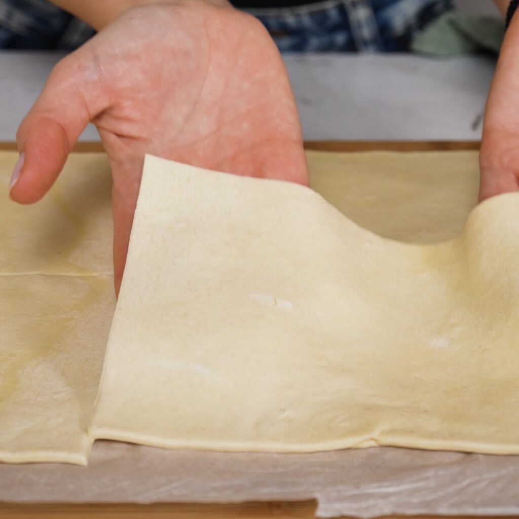 Puff pastry sheet cut into four equal rectangles on a work surface.