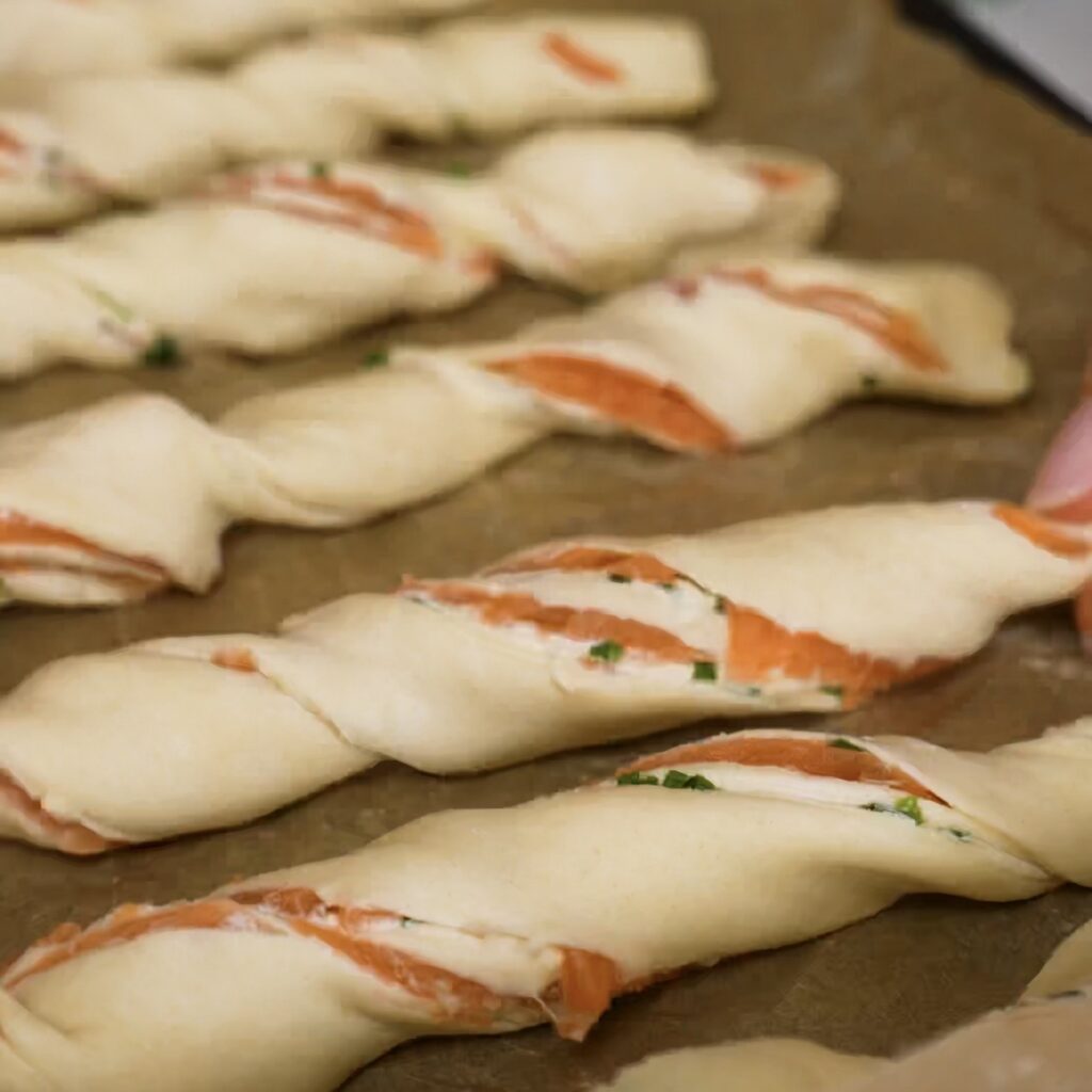Twisted puff pastry strips arranged on a baking tray.