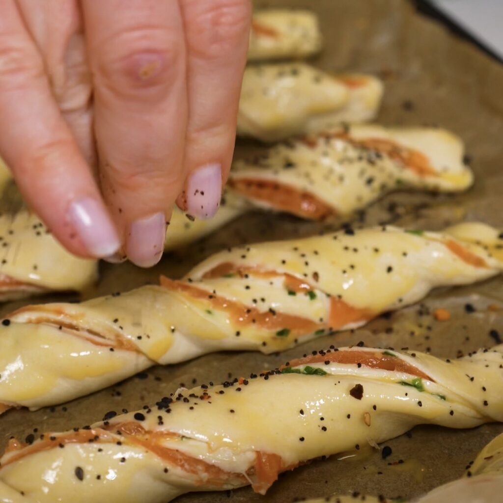 Puff pastry twists brushed with egg wash and sprinkled with sesame seeds.