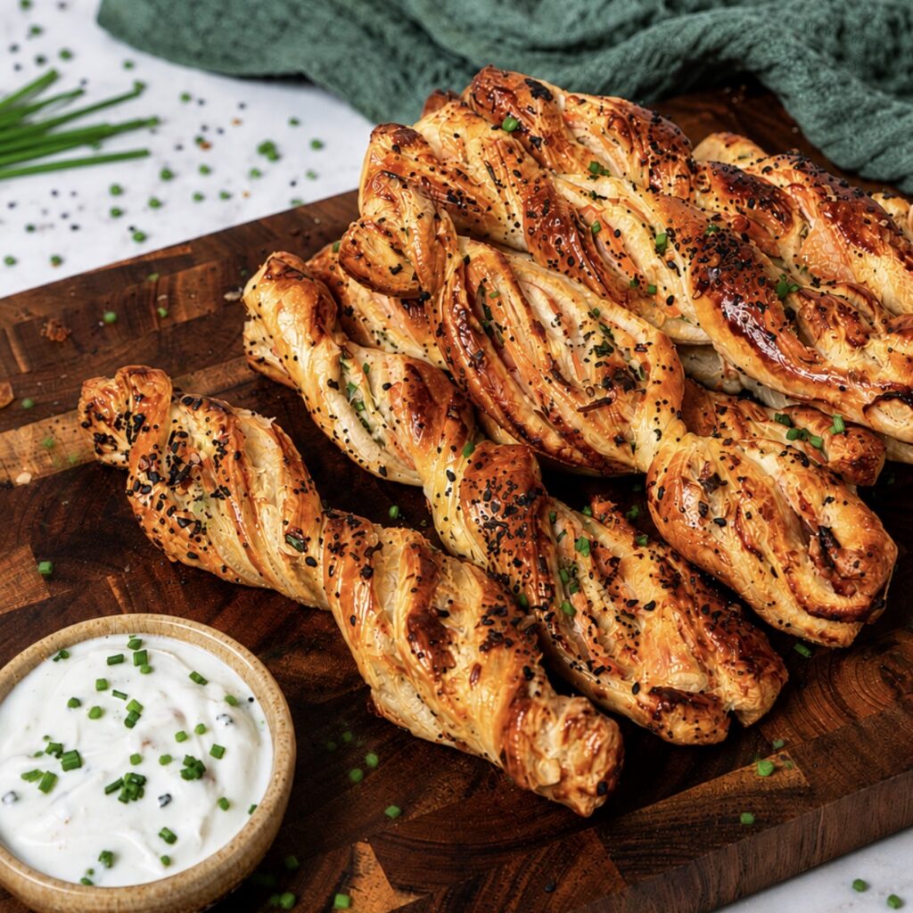 Smoked salmon puff pastry twists served on a wooden board.