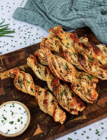 Smoked salmon puff pastry twists served on a wooden board.