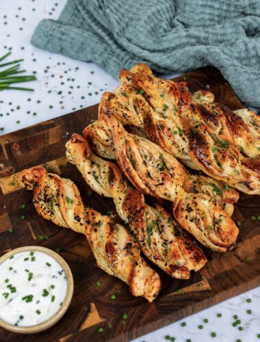 Smoked salmon puff pastry twists served on a wooden board.