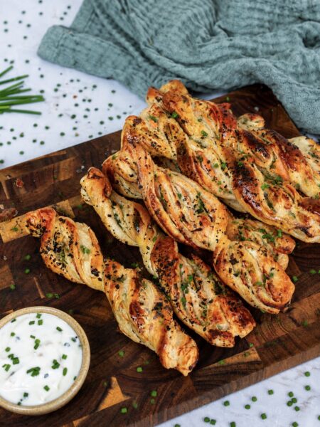 Smoked salmon puff pastry twists served on a wooden board.