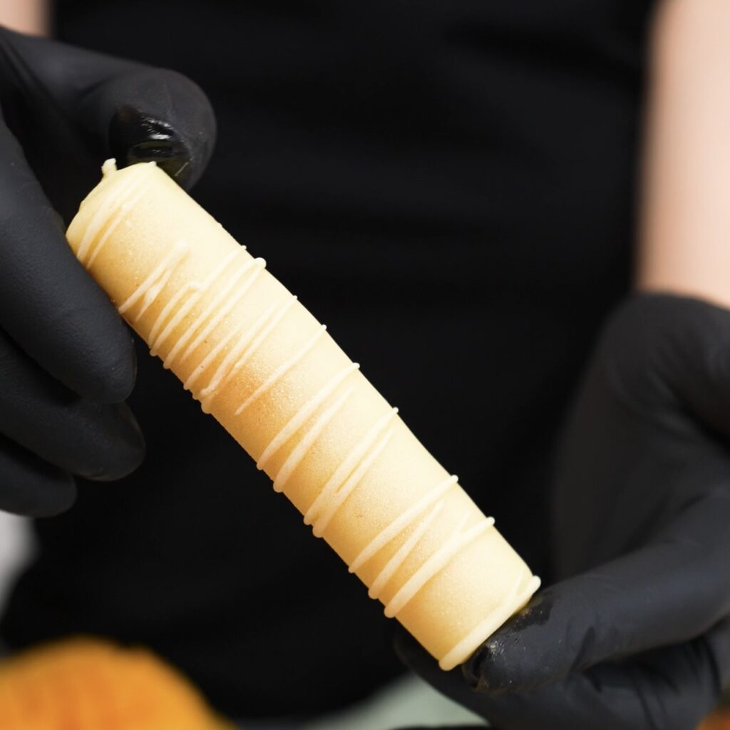 Hands holding a frozen mango yogurt bar.