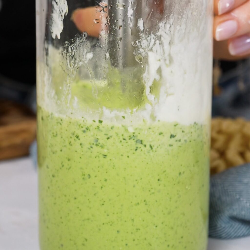 Blending cottage cheese pesto sauce with basil, pine nuts and Parmesan