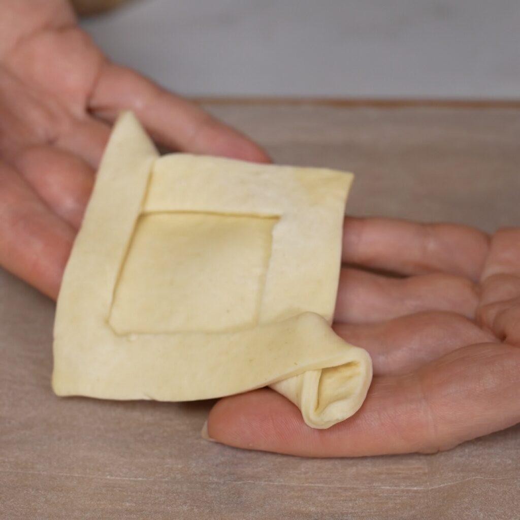 Folded puff pastry shaped into an open frame and ready to be filled.