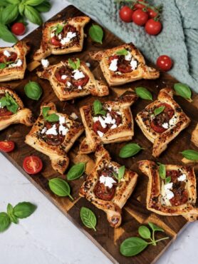 Balsamic tomato and feta puffs served on a wooden board.
