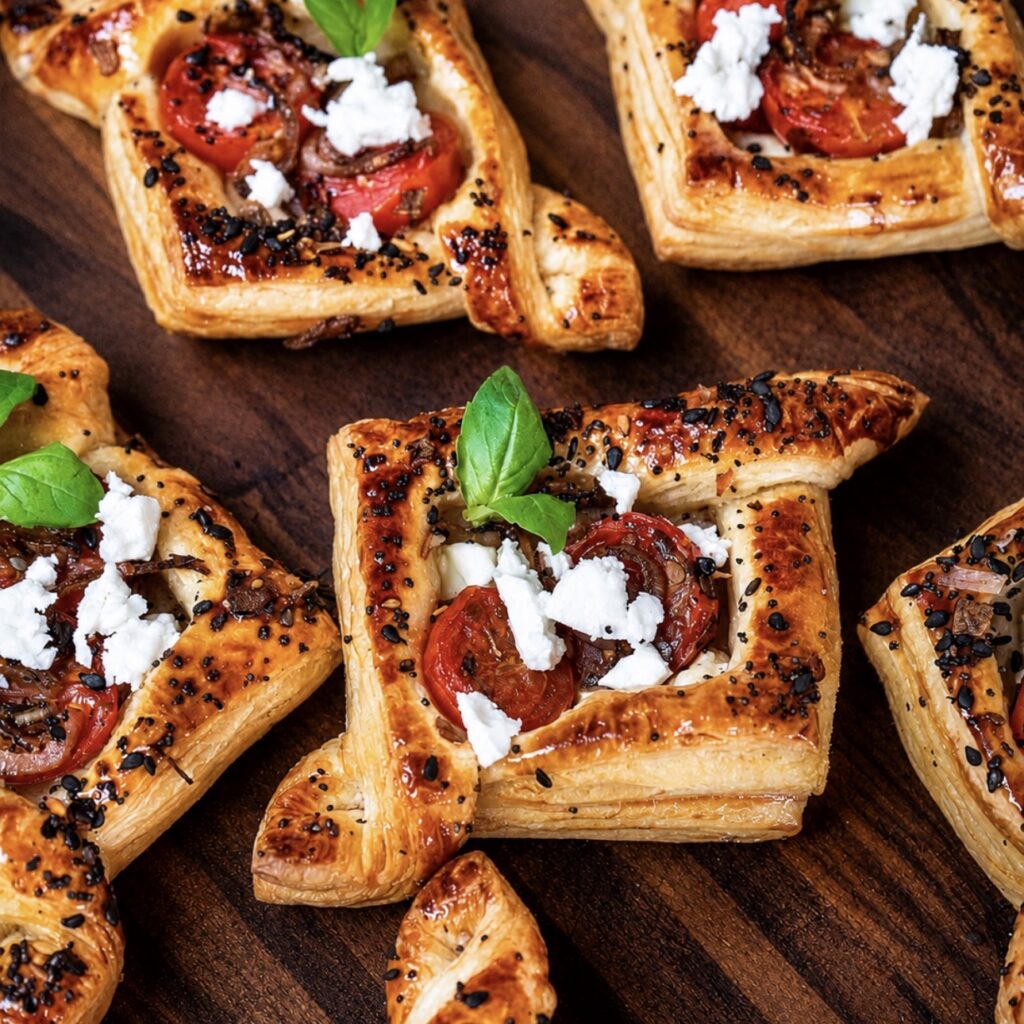 Balsamic tomato and feta puffs served on a wooden board.