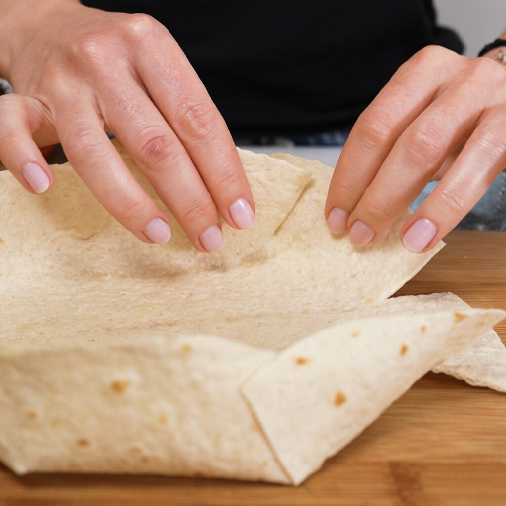 Sticking the tortilla cuts together to create a bowl-shaped quiche crust.