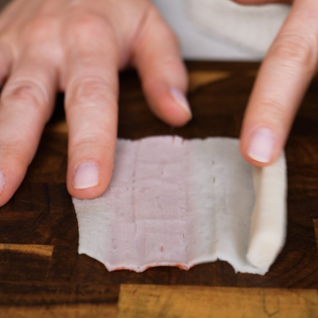Unrolling a crab stick into thin layers for crispy air fryer chips.