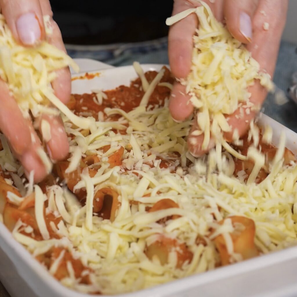 Adding grated mozzarella cheese on top of spinach and ricotta lasagna