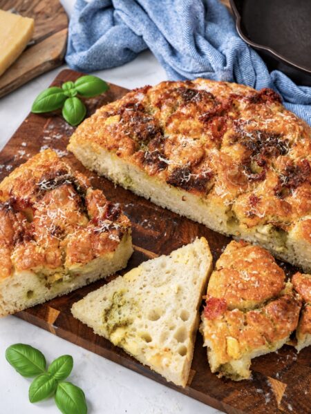 Sliced Four Cheese Pesto Focaccia served on a wooden board.