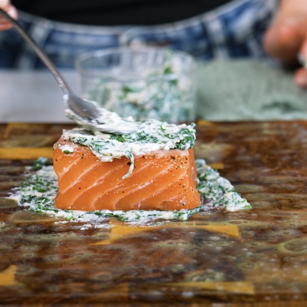Adding spinach ricotta filling on top of salmon on rice paper.