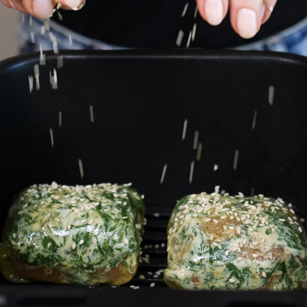 Sprinkling sesame seeds on top of rice paper salmon en croûte in the air fryer.