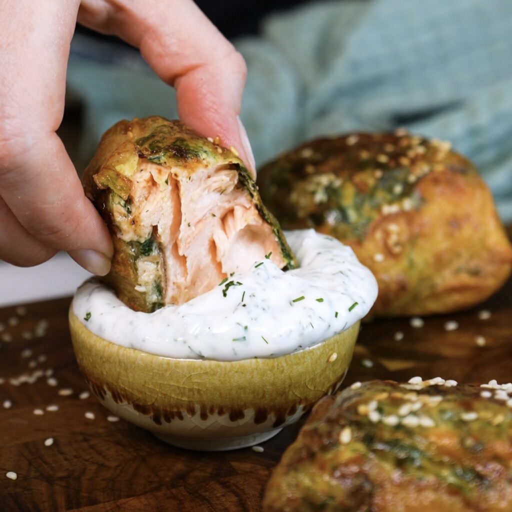 Dipping rice paper salmon en croûte into garlic yoghurt dip.