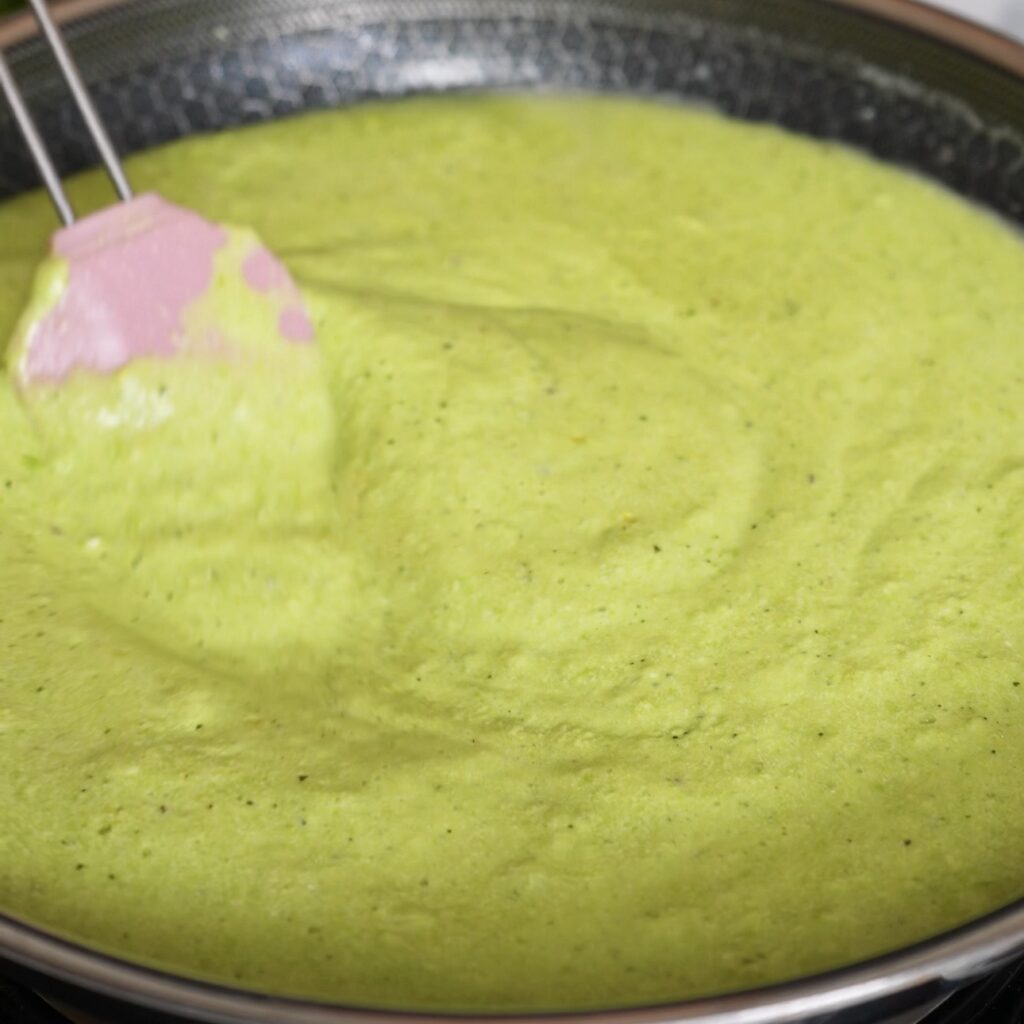 Creamy pea and mint sauce gently simmering in a pan.