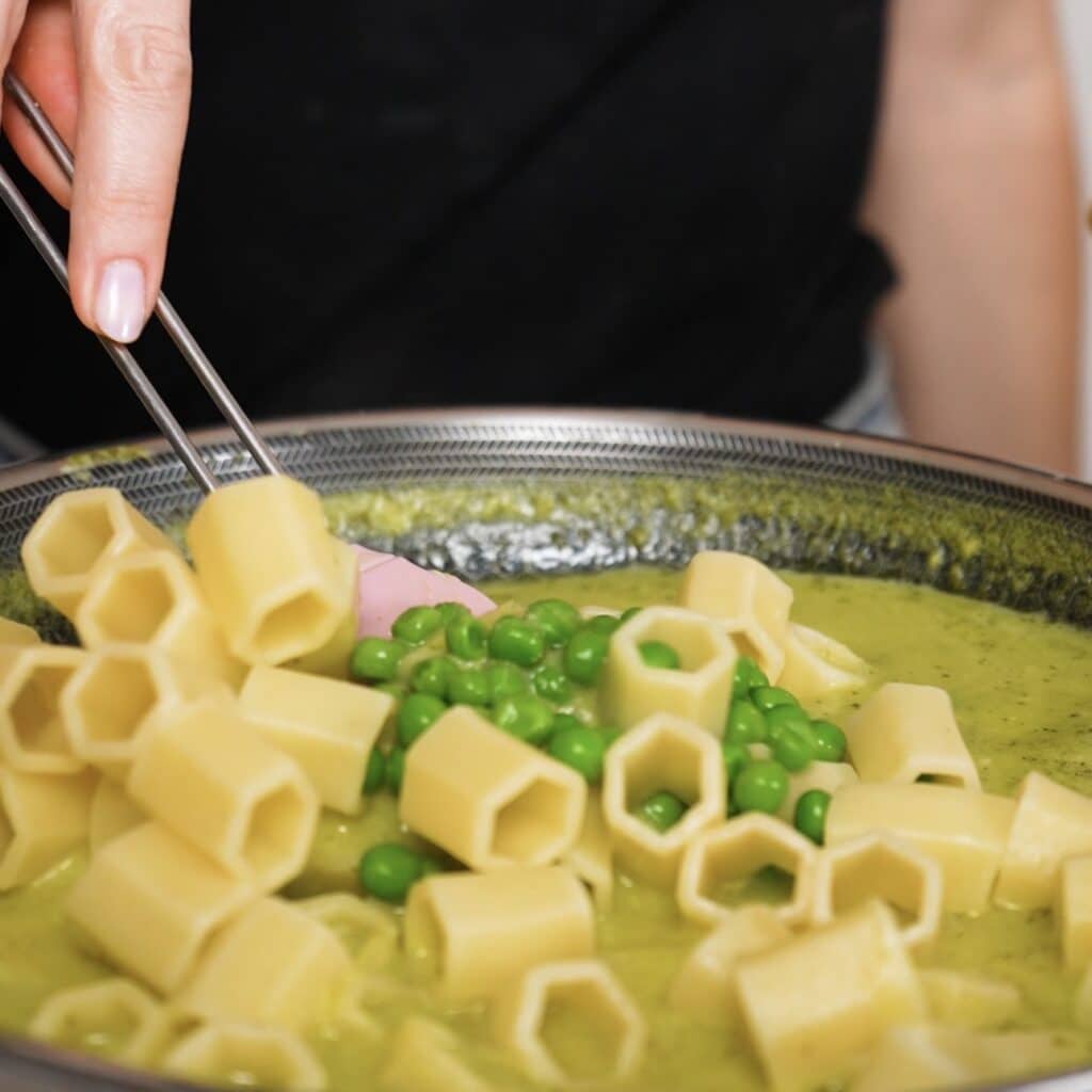 Cooked pasta and peas added to creamy pea and mint sauce in a pan.